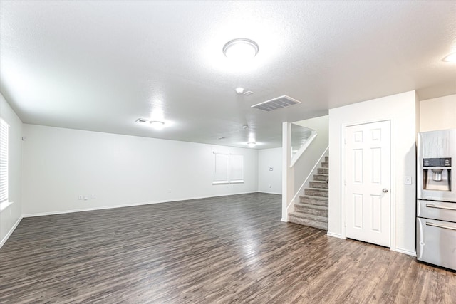 unfurnished living room featuring dark hardwood / wood-style flooring and a textured ceiling