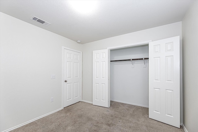 unfurnished bedroom with light colored carpet and a closet