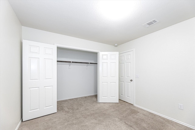 unfurnished bedroom featuring light carpet and a closet