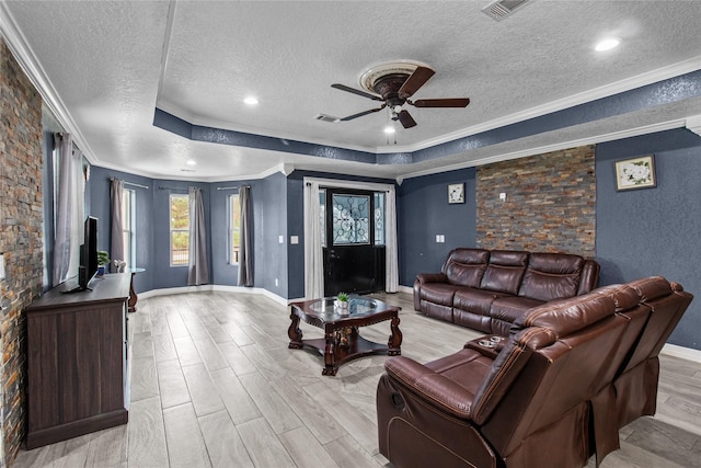 living room with a tray ceiling, ceiling fan, and ornamental molding