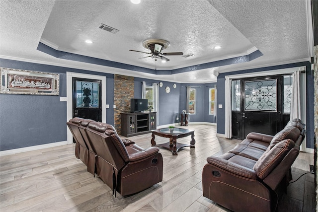 living room featuring a textured ceiling, ceiling fan, crown molding, and a tray ceiling