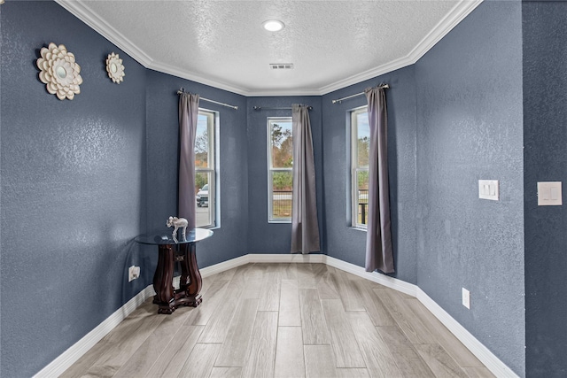 spare room featuring crown molding and a textured ceiling