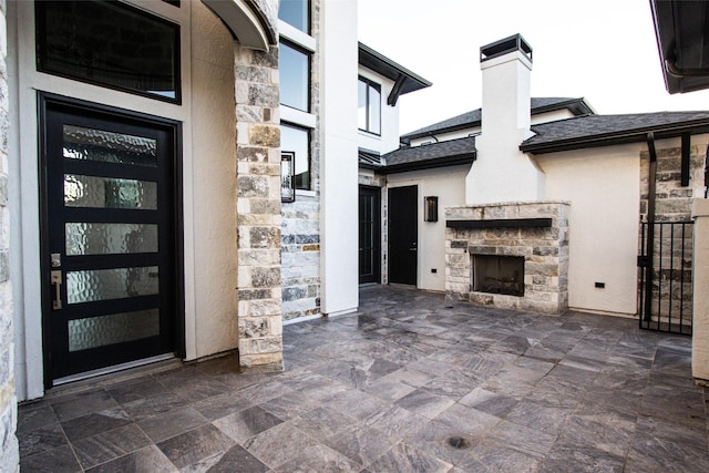 entrance to property featuring an outdoor stone fireplace and a patio