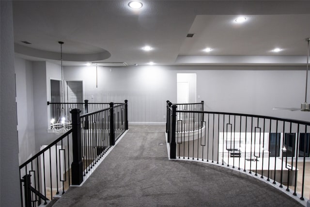 hallway with carpet floors and a raised ceiling