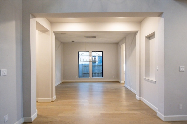 hallway with light hardwood / wood-style flooring and an inviting chandelier