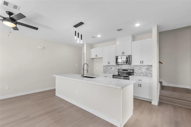 kitchen with sink, white cabinets, stainless steel appliances, and a center island with sink