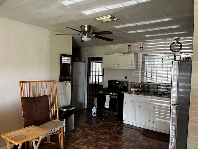 kitchen featuring black gas range oven, dark parquet floors, ceiling fan, white cabinets, and stainless steel refrigerator