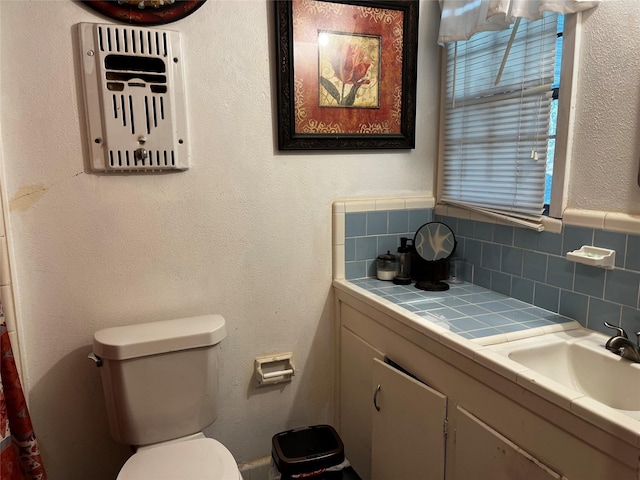 bathroom featuring vanity, toilet, and tasteful backsplash