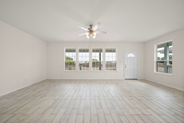 empty room featuring ceiling fan, light wood-type flooring, and a wealth of natural light