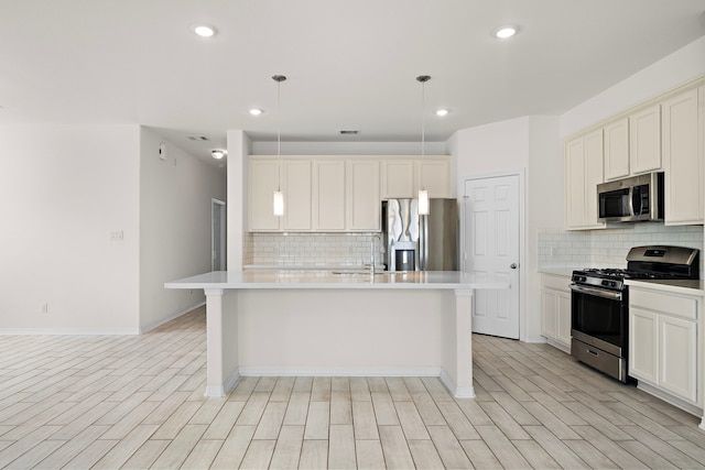 kitchen with decorative backsplash, pendant lighting, stainless steel appliances, and a center island with sink