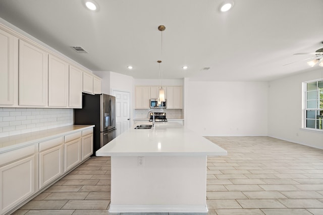 kitchen featuring pendant lighting, white cabinets, sink, an island with sink, and appliances with stainless steel finishes