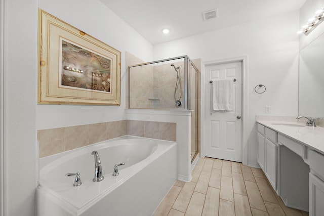 bathroom featuring hardwood / wood-style flooring, vanity, and plus walk in shower