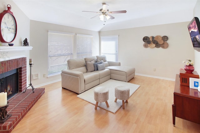 living room featuring ceiling fan, light wood-type flooring, and a fireplace