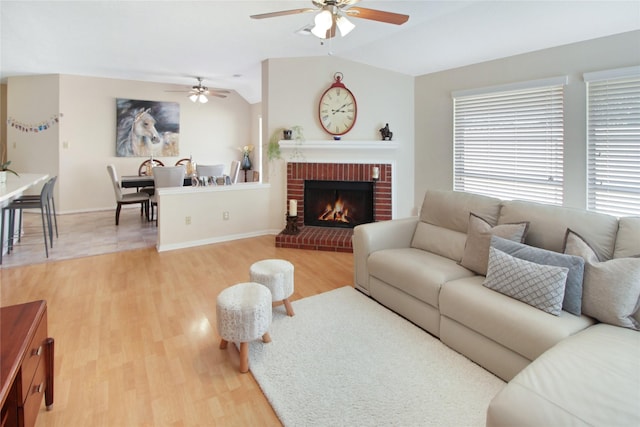 living room featuring ceiling fan, wood-type flooring, lofted ceiling, and a brick fireplace