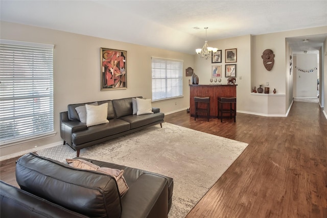 living room featuring a wealth of natural light, dark wood-type flooring, a chandelier, and lofted ceiling