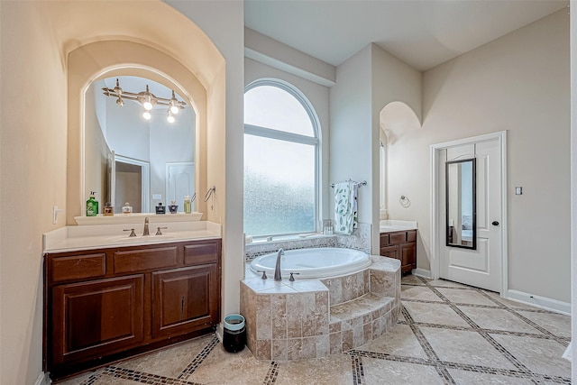 bathroom featuring vanity, tiled tub, and a chandelier