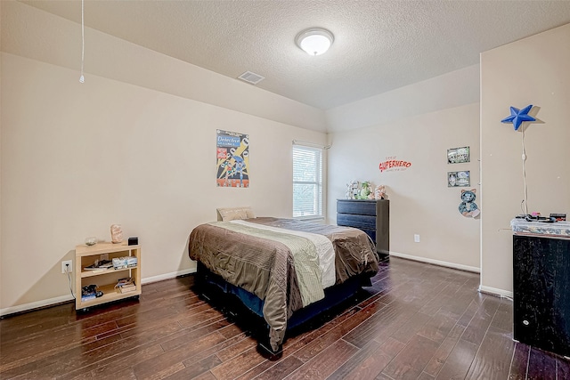 bedroom with dark hardwood / wood-style floors and a textured ceiling