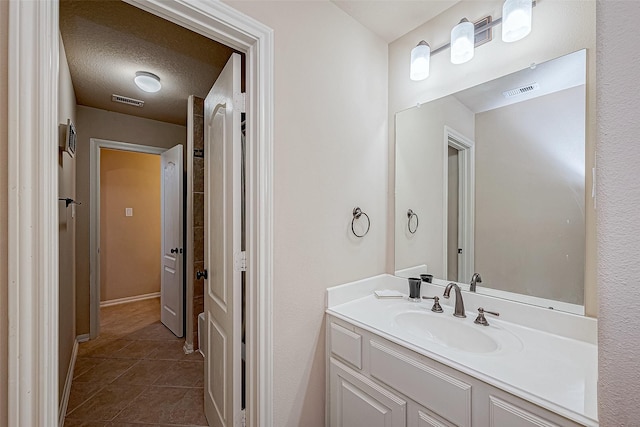 bathroom with tile patterned floors, vanity, and a textured ceiling