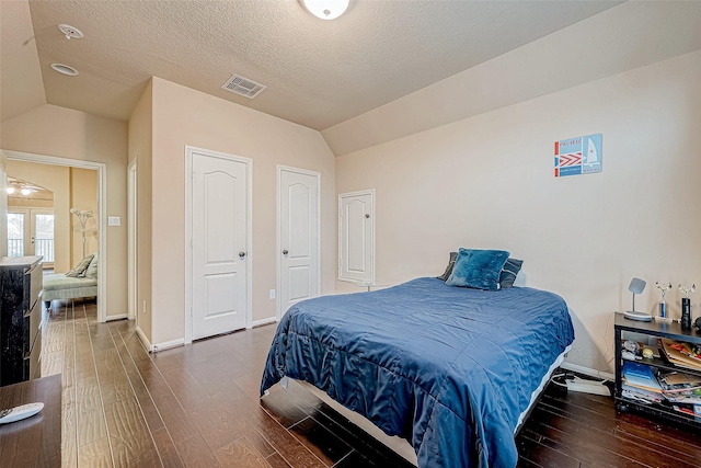 bedroom with a textured ceiling, lofted ceiling, french doors, and dark hardwood / wood-style floors