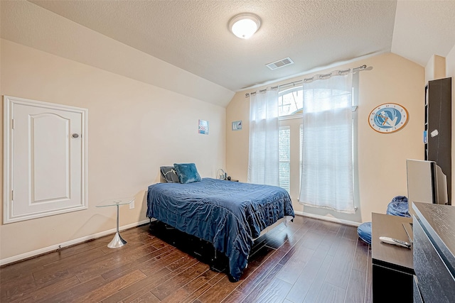 bedroom with dark hardwood / wood-style flooring, lofted ceiling, and a textured ceiling