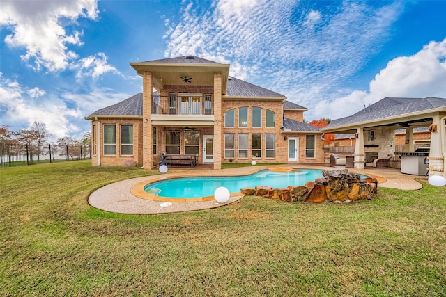 view of swimming pool with a yard, ceiling fan, a patio area, and exterior kitchen