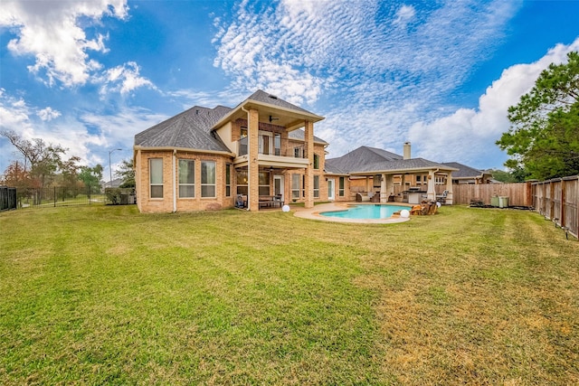 back of house with a balcony, a fenced in pool, and a lawn