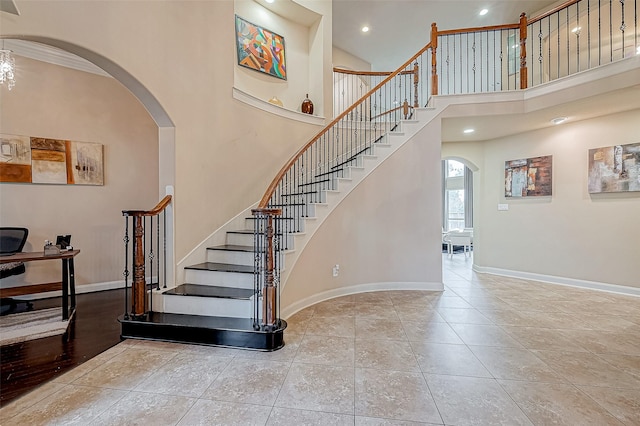 stairs with tile patterned floors and a towering ceiling