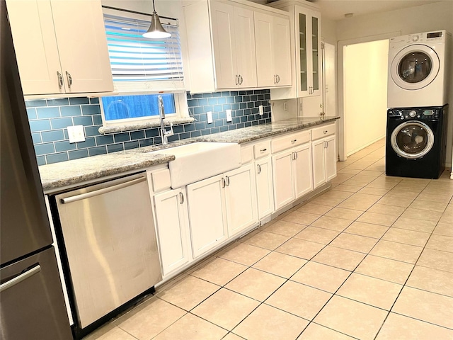 kitchen featuring white cabinetry, stainless steel appliances, light stone counters, decorative light fixtures, and stacked washer / drying machine