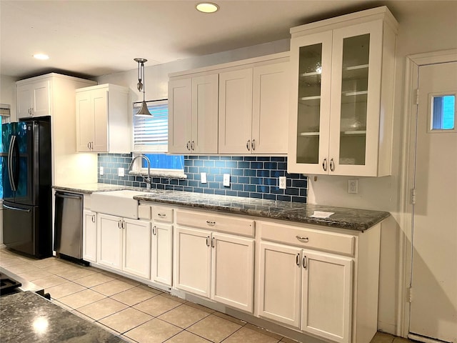 kitchen featuring black fridge, stainless steel dishwasher, sink, light tile patterned floors, and decorative light fixtures