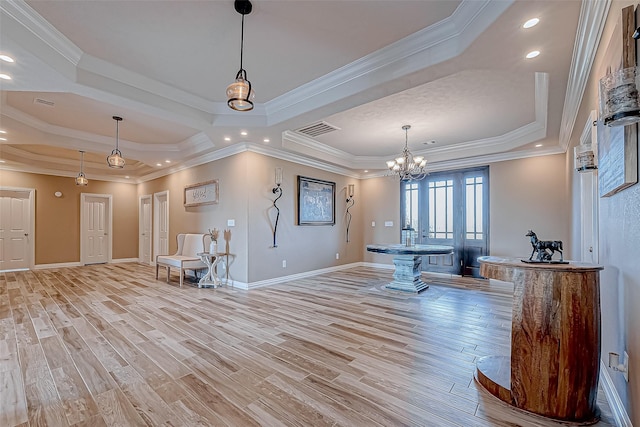 interior space featuring a tray ceiling, an inviting chandelier, light hardwood / wood-style floors, and ornamental molding