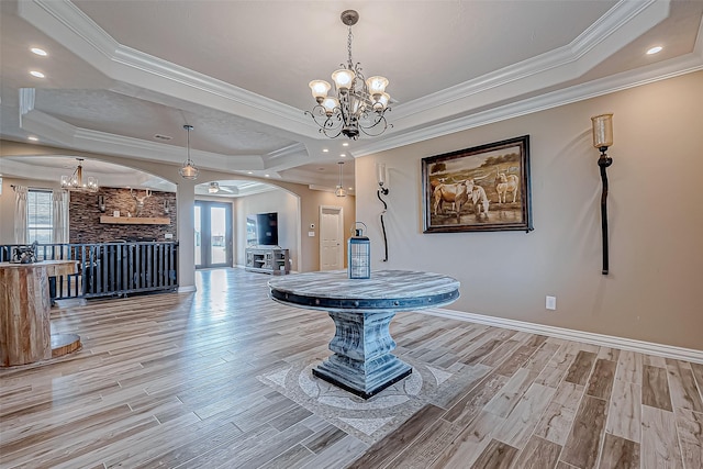 dining area featuring french doors, ornamental molding, a tray ceiling, light hardwood / wood-style floors, and a chandelier