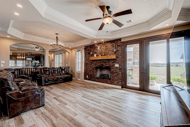 living room with a raised ceiling, french doors, light hardwood / wood-style floors, and a textured ceiling