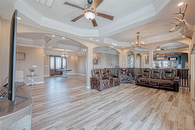 living room with ceiling fan with notable chandelier, light hardwood / wood-style floors, a raised ceiling, and ornamental molding