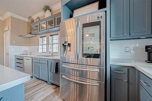 kitchen featuring appliances with stainless steel finishes, light wood-type flooring, crown molding, sink, and range hood