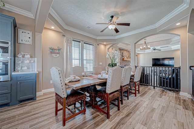 dining room with a textured ceiling, ceiling fan with notable chandelier, light hardwood / wood-style flooring, and ornamental molding