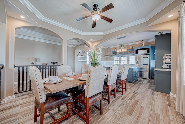 dining area featuring ceiling fan with notable chandelier, built in features, ornamental molding, and light hardwood / wood-style flooring