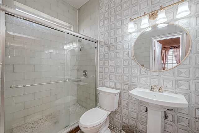 bathroom featuring a shower with door, tile walls, and toilet