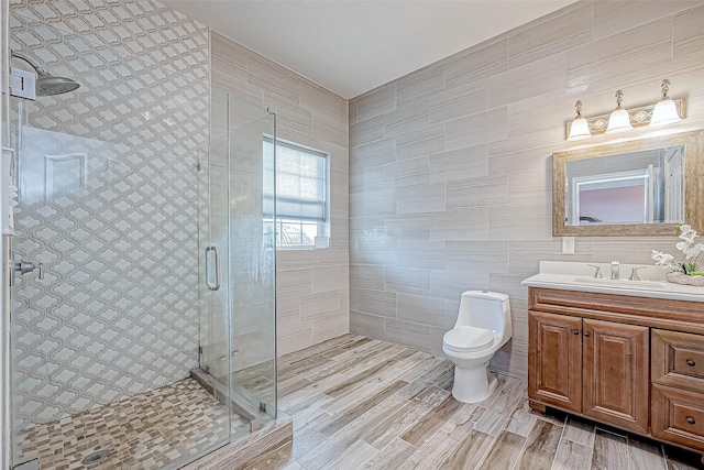 bathroom with vanity, hardwood / wood-style flooring, toilet, tile walls, and an enclosed shower