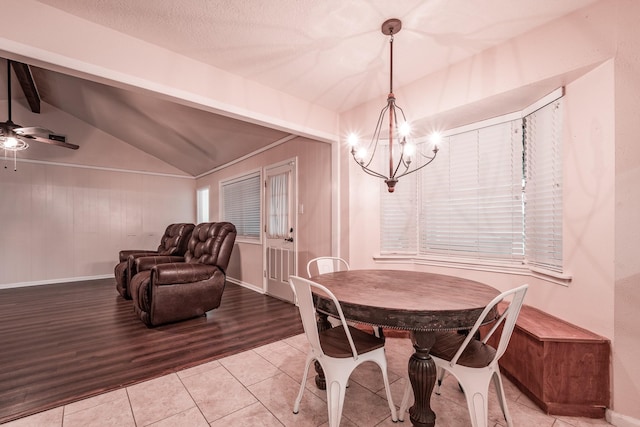 dining area with ceiling fan with notable chandelier, vaulted ceiling with beams, and light tile patterned flooring