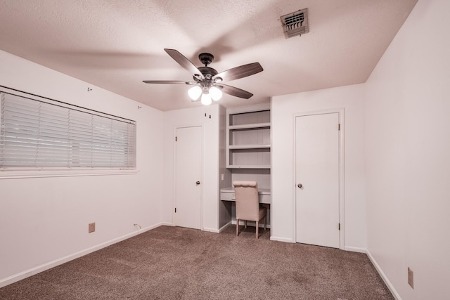 unfurnished bedroom with ceiling fan, dark carpet, and a textured ceiling