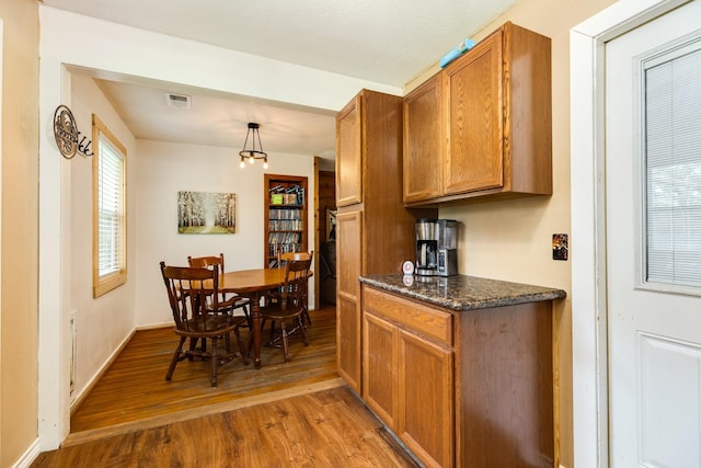 kitchen featuring hardwood / wood-style floors, decorative light fixtures, and dark stone countertops