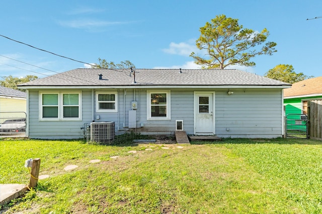 rear view of property with central AC unit and a yard