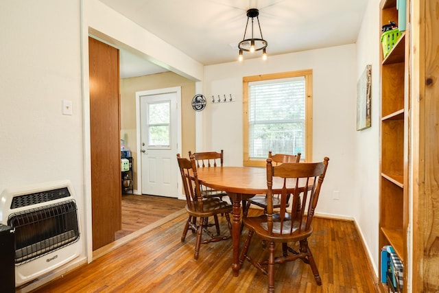 dining area featuring a wealth of natural light, heating unit, hardwood / wood-style flooring, and a notable chandelier