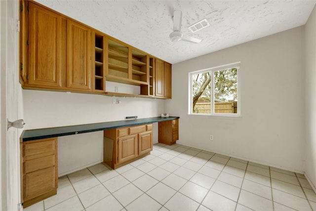 kitchen featuring ceiling fan, built in desk, and a textured ceiling