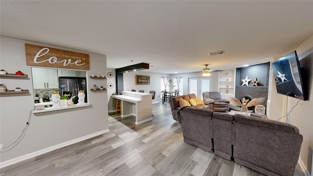 living room with a fireplace, light wood-type flooring, and ceiling fan