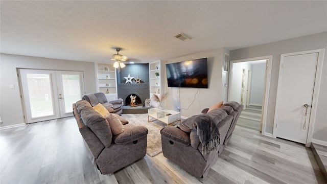 living room featuring a fireplace, french doors, light hardwood / wood-style flooring, and ceiling fan