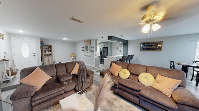 living room featuring ceiling fan and a textured ceiling