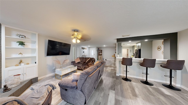 living room with light hardwood / wood-style flooring, built in features, and ceiling fan