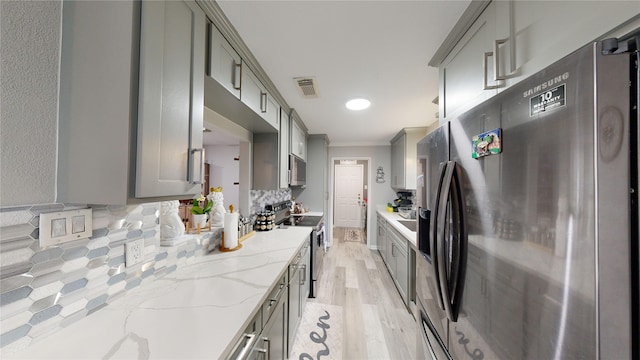 kitchen featuring gray cabinets, light stone countertops, and appliances with stainless steel finishes