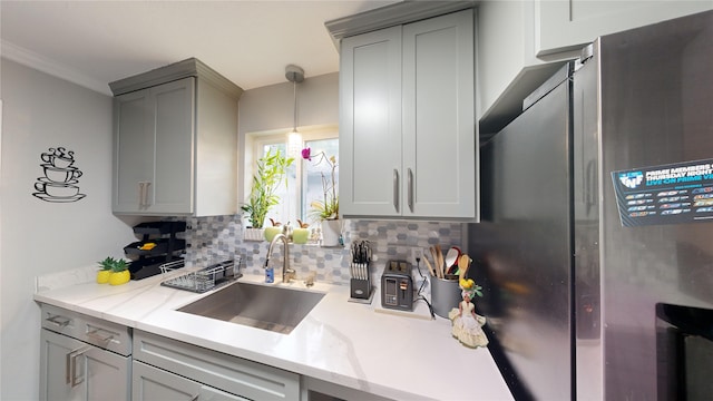 kitchen featuring stainless steel fridge, tasteful backsplash, gray cabinetry, and sink